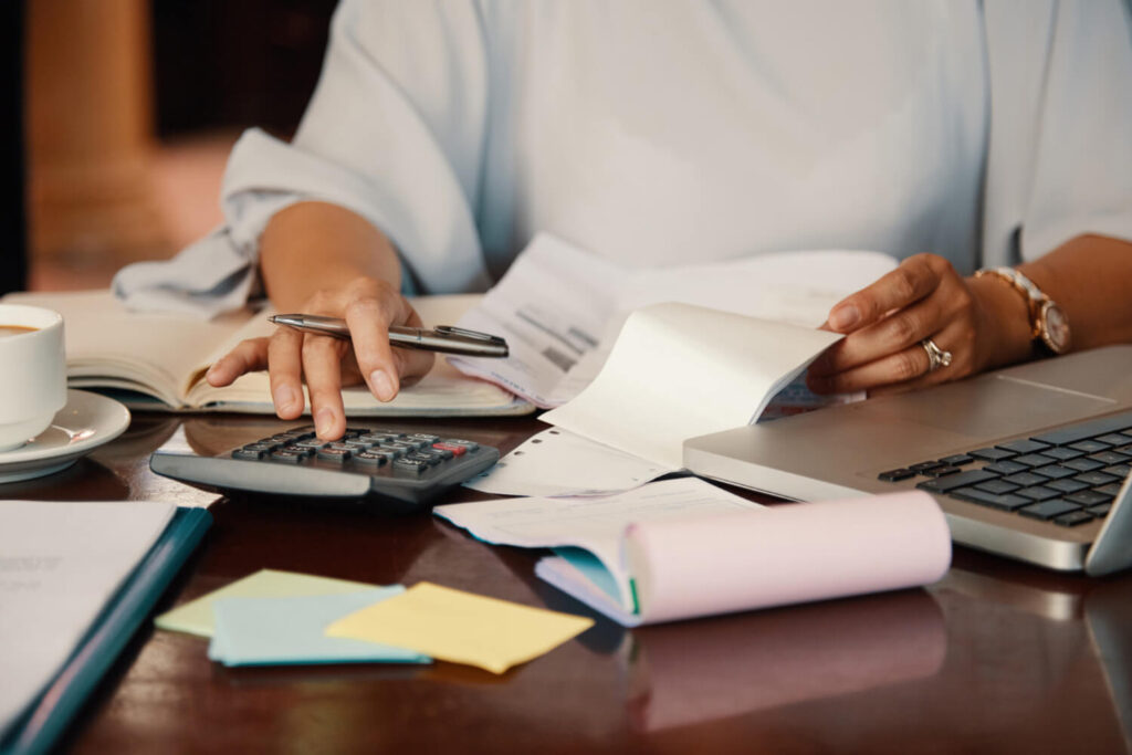Mujer revisando papeles y usando una calculadora