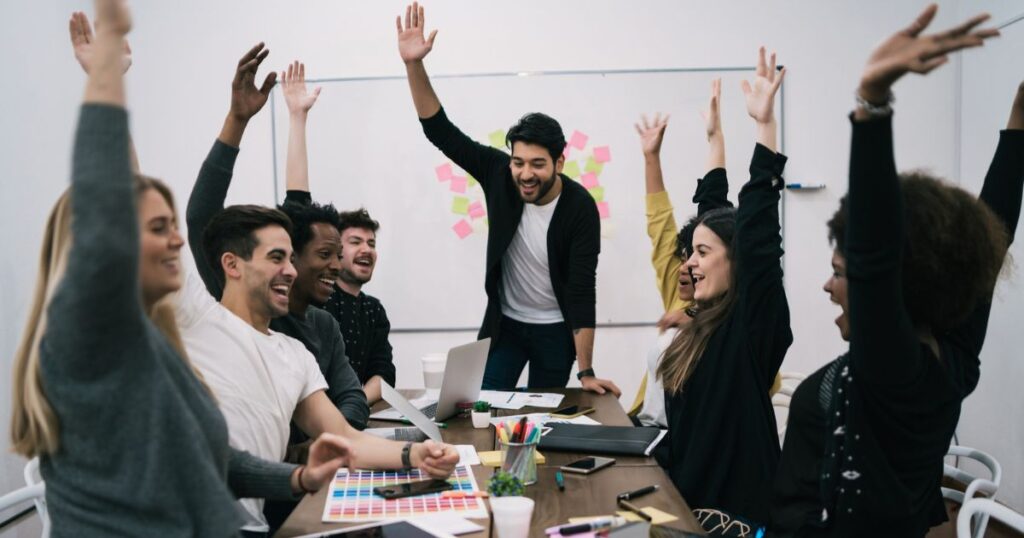 Equipo de trabajo feliz levantando las manos en la oficina