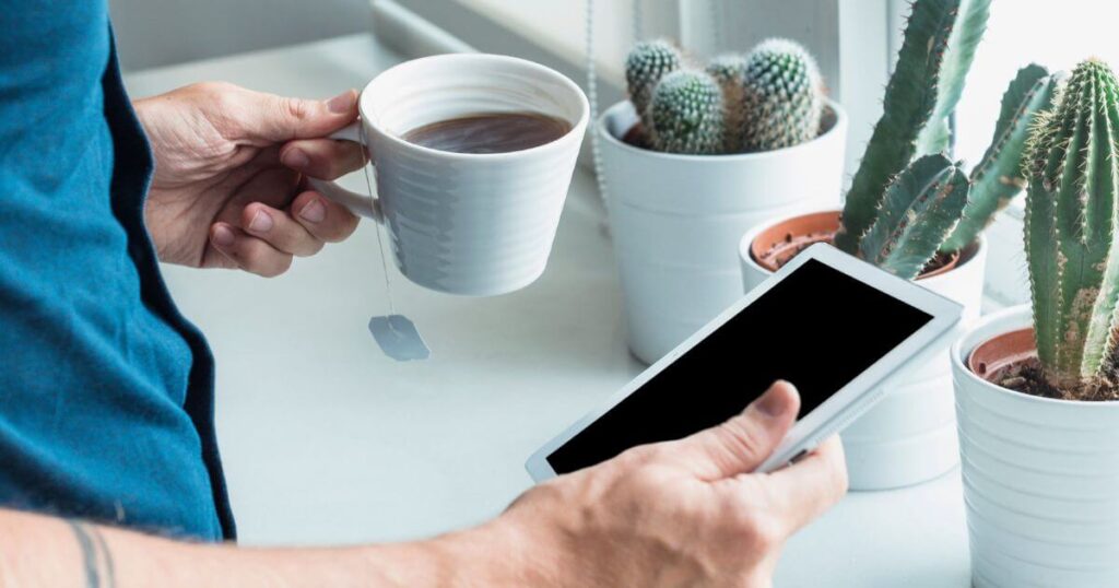 Hombre sosteniendo un teléfono y un café en la oficina