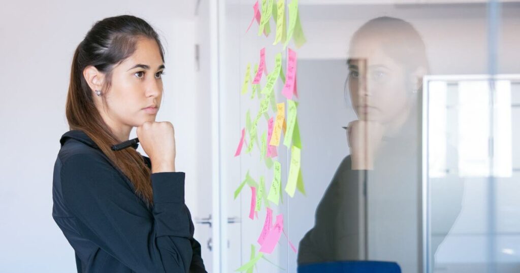Mujer observando diferfentes notas mientras piensa concentrada
